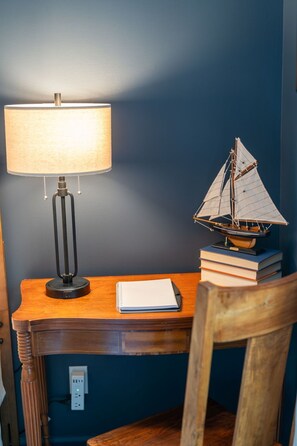 Ein Schreibtisch mit einer Lampe, einem Modellschiff und einem Notizbuch.