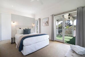 A bedroom with a large bed, a nightstand, a window, and a view of a balcony. - Willow Landing Beach House with Private Jetty (Frankston)