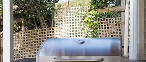 A portable barbecue grill with a control panel and a storage cabinet, set up outdoors.