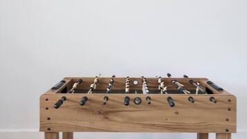 A wooden foosball table with a classic design, positioned against a plain wall.