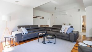 Een moderne woonkamer met een modulaire bank, een ronde salontafel en een vloerlamp.