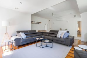 A modern living room with a sectional sofa, a round coffee table, and a floor lamp. - Willow Landing Beach House with Private Jetty (Frankston)