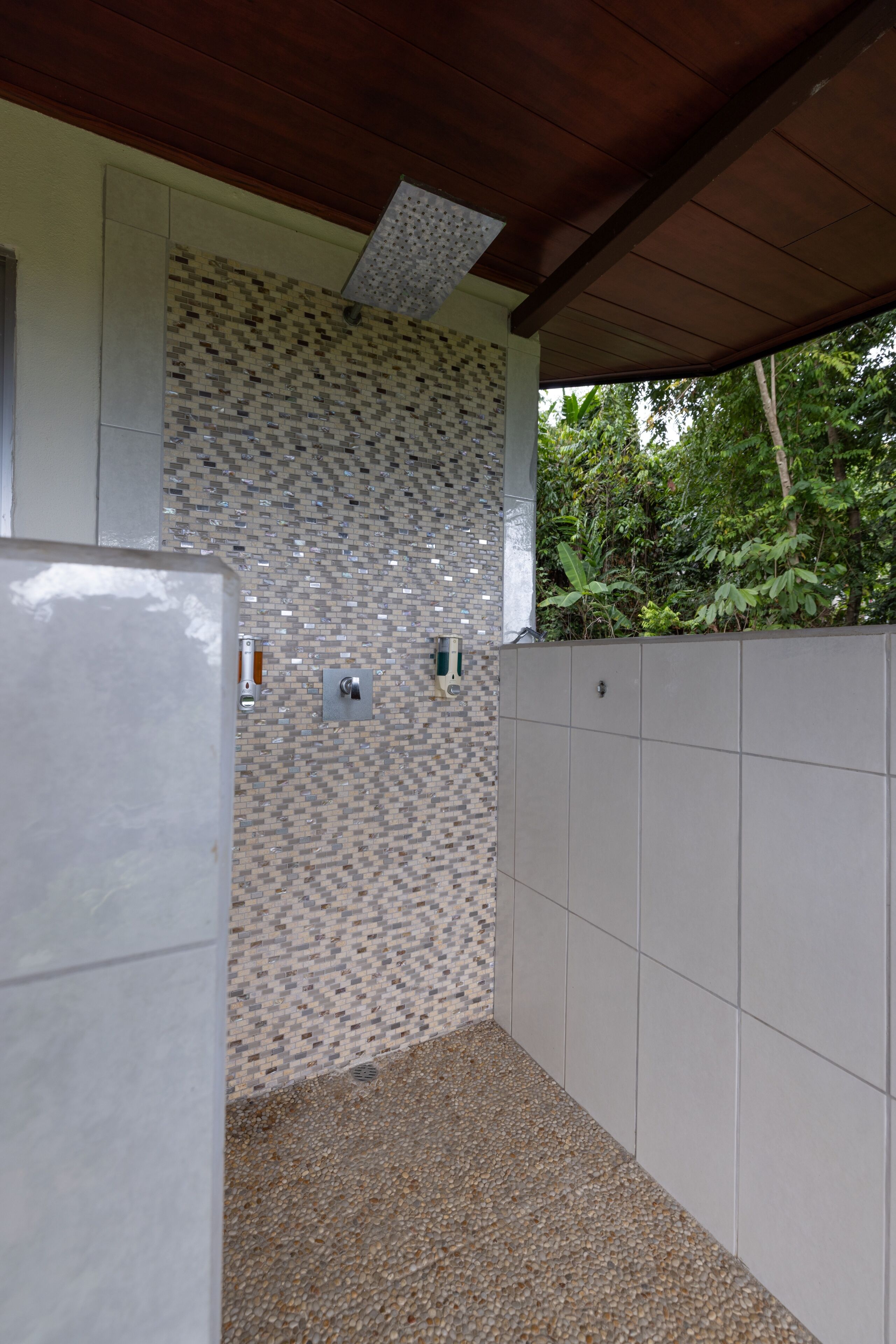 A covered outdoor area with a tiled wall, a metal door, and a concrete wall.