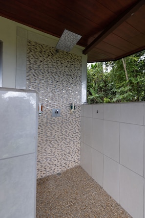 A covered outdoor area with a tiled wall, a metal door, and a concrete wall. - Casa Odi-Sea 2.0 (Savegre)