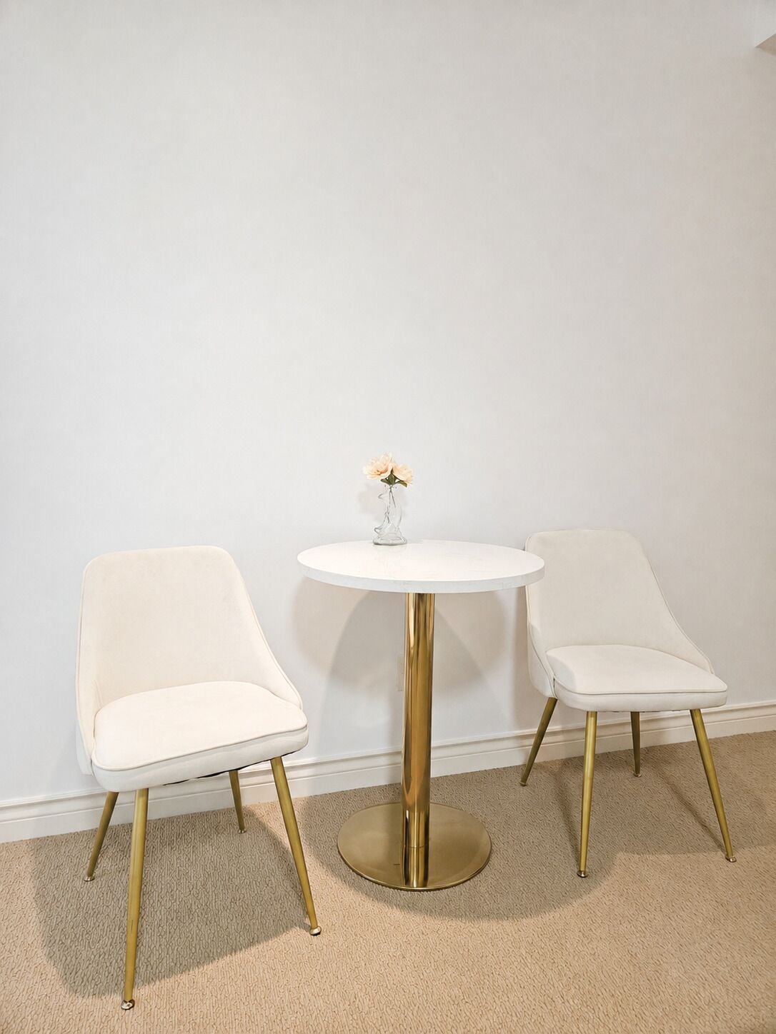 Une pièce avec une table ronde et deux chaises aux pieds dorés.