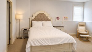A bedroom with a large bed, bedside tables, a chair, and a window.