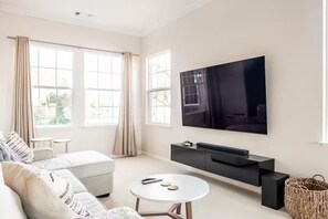 A modern living room with a large flat-screen TV, a sofa, a coffee table, and a black entertainment unit.