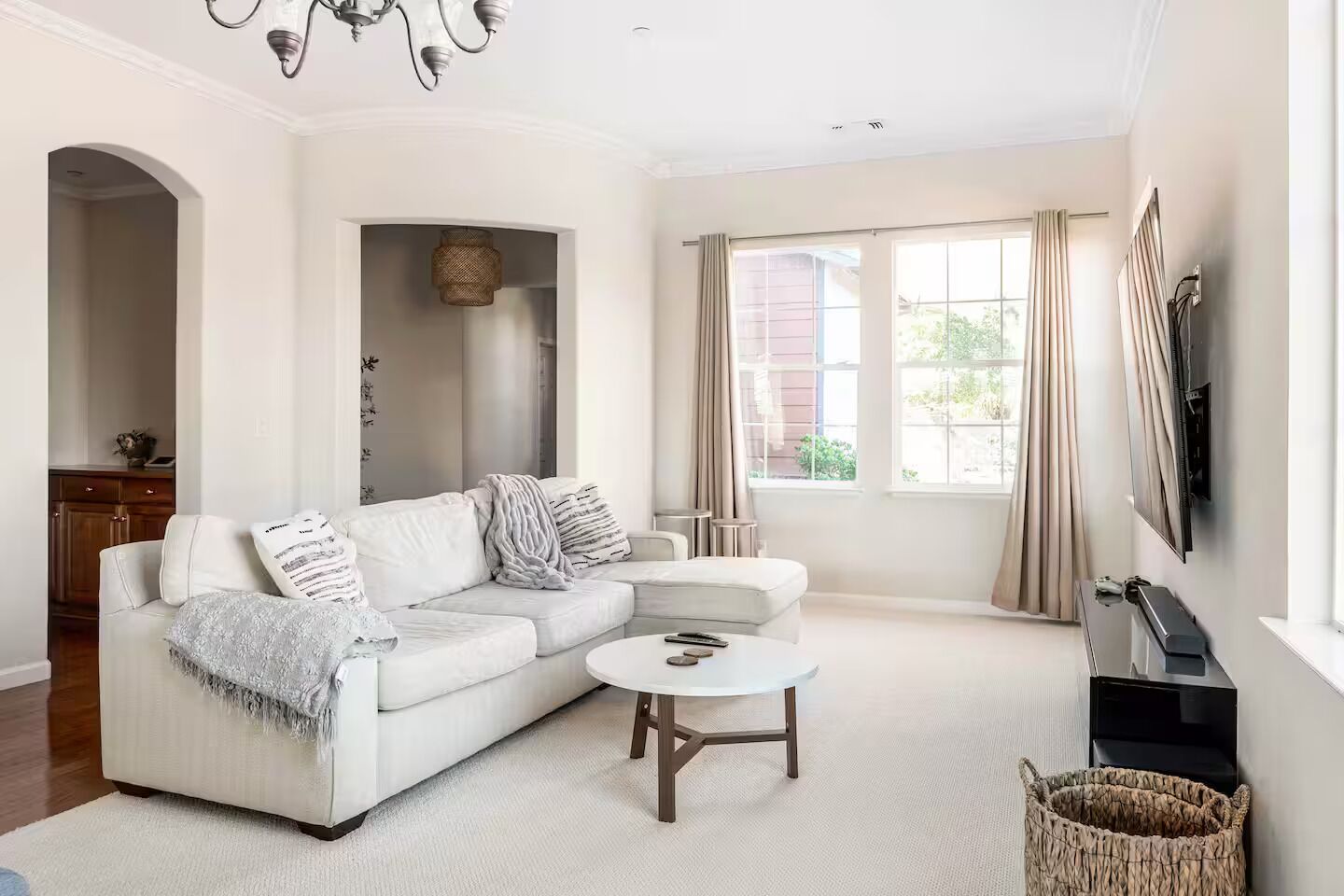 A modern living room with a sectional sofa, a round coffee table, and a television mounted on the wall.