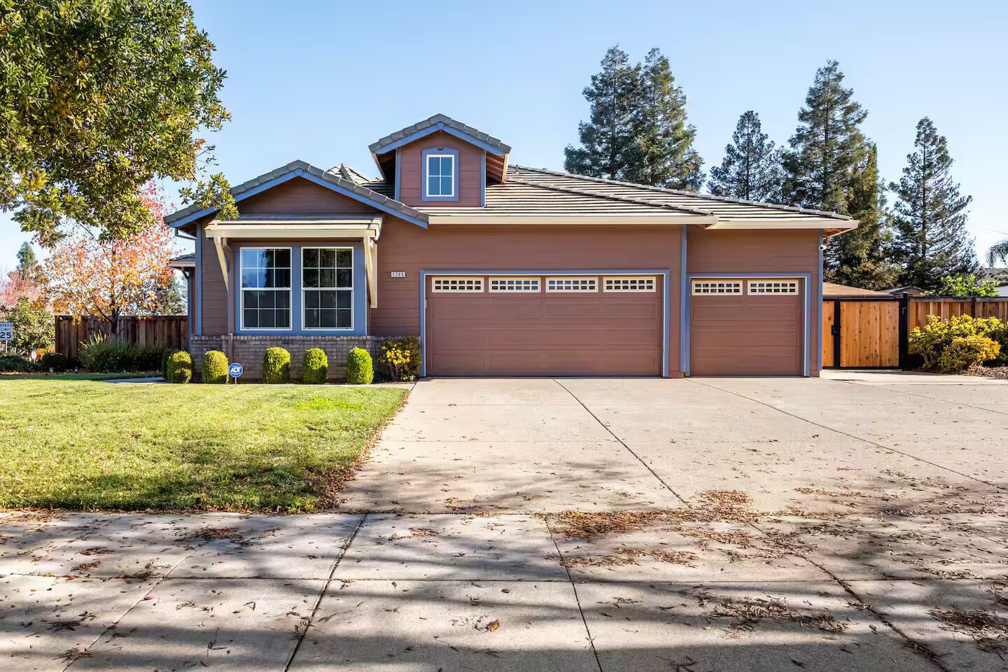 A two-story house with a garage, a covered driveway, and a well-maintained lawn.