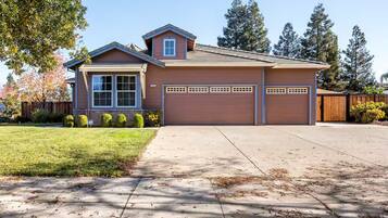 A two-story house with a garage, a covered driveway, and a well-maintained lawn.