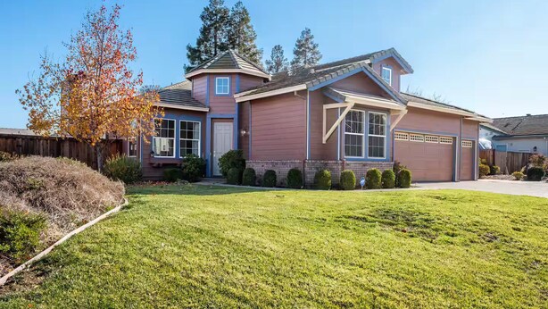 A two-story house with a large front lawn, a garage, and a covered porch. - home away from home spacious 3b 2b mobile home covered back porch with hot tub.. (seven points)