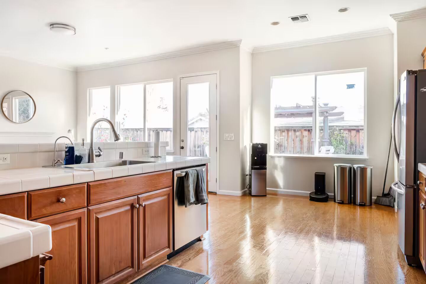Una cocina con encimera de madera, un lavamanos, lavavajillas, dispensador de agua y una ventana con vista a un patio trasero.