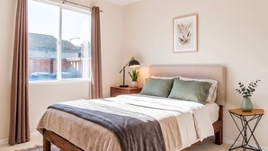 A bedroom with a bed, nightstand, lamp, and a window with curtains. - home away from home spacious 3b 2b mobile home covered back porch with hot tub.. (seven points)