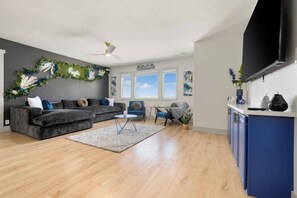 A modern living room with a grey sectional sofa, a small round coffee table, and a blue armchair. - Experience Serenity and Style in a Ryde Retreat. 8  Guests 2 bd 2ba, 3 Car Gar (Walnut Grove)