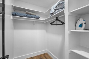 A walk-in closet with white shelves, a hanging rack, and a wooden floor. - Modern Getaway & Casita Near the Domain + Fire Pit Backyard, Sleeps 8 (Austin)