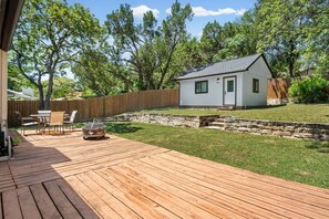 Eine Terrasse mit Gartenmöbeln, ein kleines Haus und eine Steinmauer.