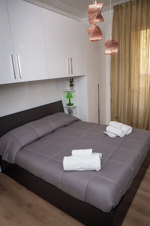 A modern bedroom with a large bed, white cabinets, a green lamp, and a decorative plant. - A beautiful and very comfortable apartment in Rome, with two bedrooms, a living room, a kitchen, and a bathroom (Roma)