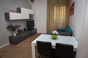 A modern living space with a dining table, chairs, a TV, and a sofa. - A beautiful and very comfortable apartment in Rome, with two bedrooms, a living room, a kitchen, and a bathroom (Roma)