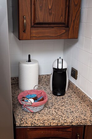 A kitchen counter with a paper towel roll, a coffee maker, and a basket containing jars. - A beautiful and very comfortable apartment in Rome, with two bedrooms, a living room, a kitchen, and a bathroom (Roma)