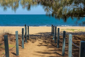 A sandy beach path leading to the ocean, surrounded by wooden posts and chains. - Beachfront Home Townsville (Pallarenda)