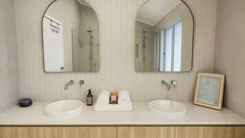 A bathroom with two sinks, a mirror, and a framed picture.