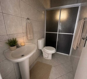 Ein Badezimmer mit Waschbecken, Toilette und Duschbereich.
