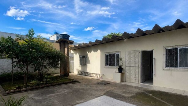 Um edifício residencial com um pátio com telhado, um reservatório no telhado e uma entrada com portão.