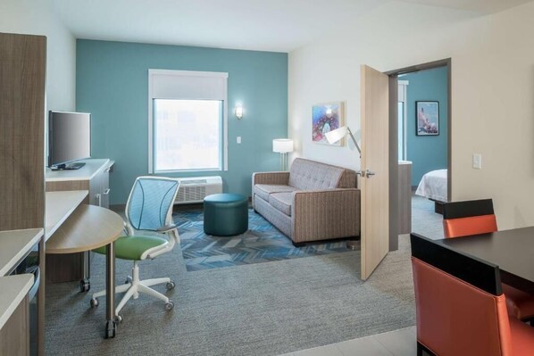 Ein Hotelzimmer mit Schreibtisch, Stuhl, einer Couch und einem Bett.