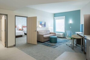 Ein Hotelzimmer mit einem Bett, einer Couch, einem Schreibtisch, einem Sessel und einem Fenster.