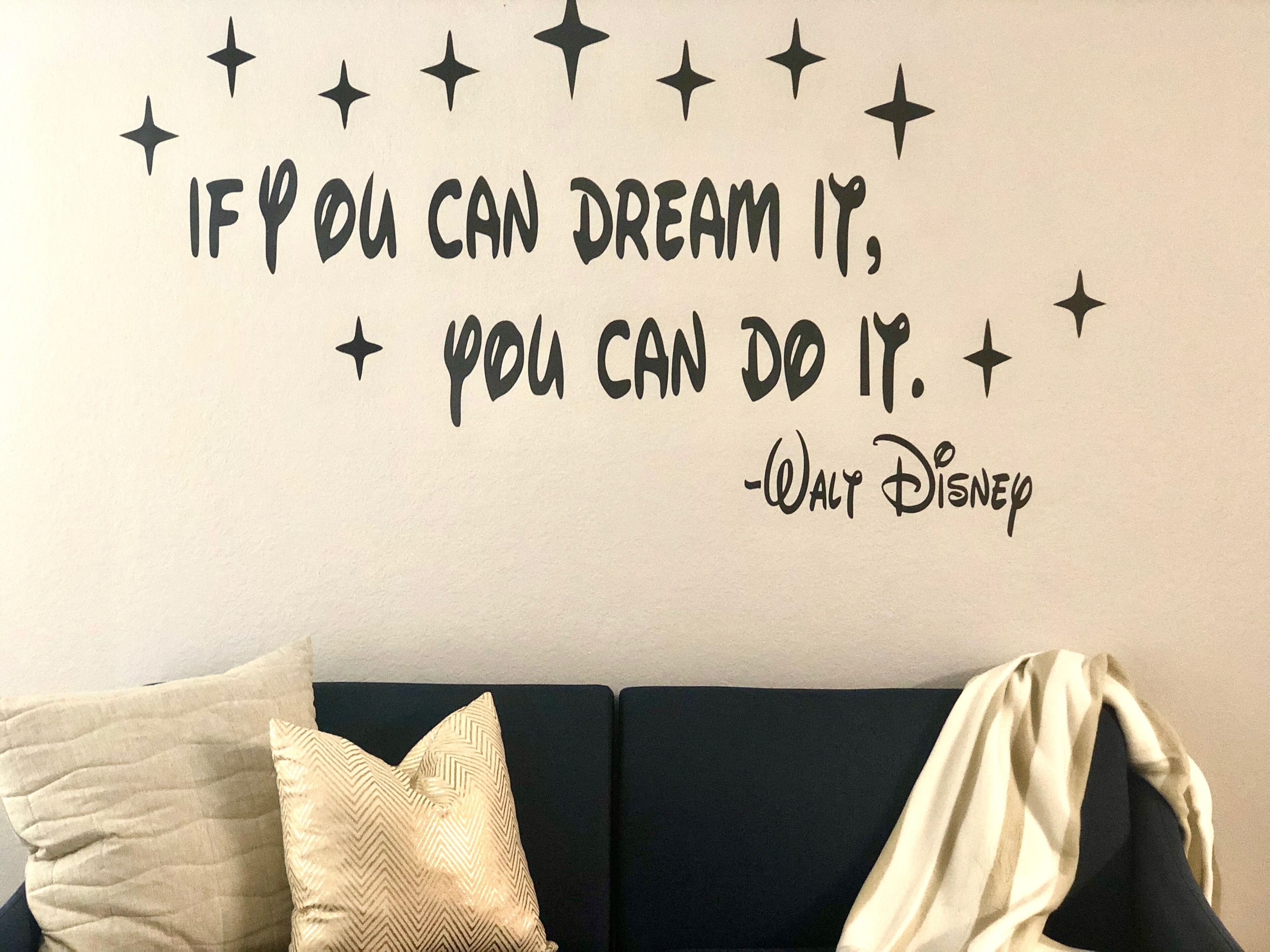A wall with a motivational quote and a couch with pillows.