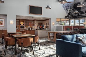 Eine moderne Küche mit Holzausstattung, ein Essbereich mit Ledersesseln und ein blaues Sofa.