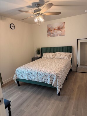 A bedroom with a bed, a ceiling fan, a clock, and a wall art piece. - 3-bedroom house in lovely Lubbock with AC for your stay (Lubbock)