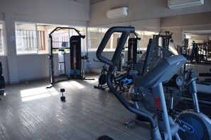 A gym with various exercise equipment, including a red zone elliptical, a weight machine, and a bench press. - Santa Marta: Sunset View, Pools, and Private Beach in Pozos Colorados (Santa Marta)