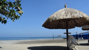 A beach with a thatched umbrella, a volleyball net, and a clear blue sky. - Santa Marta: Sunset View, Pools, and Private Beach in Pozos Colorados (Santa Marta)