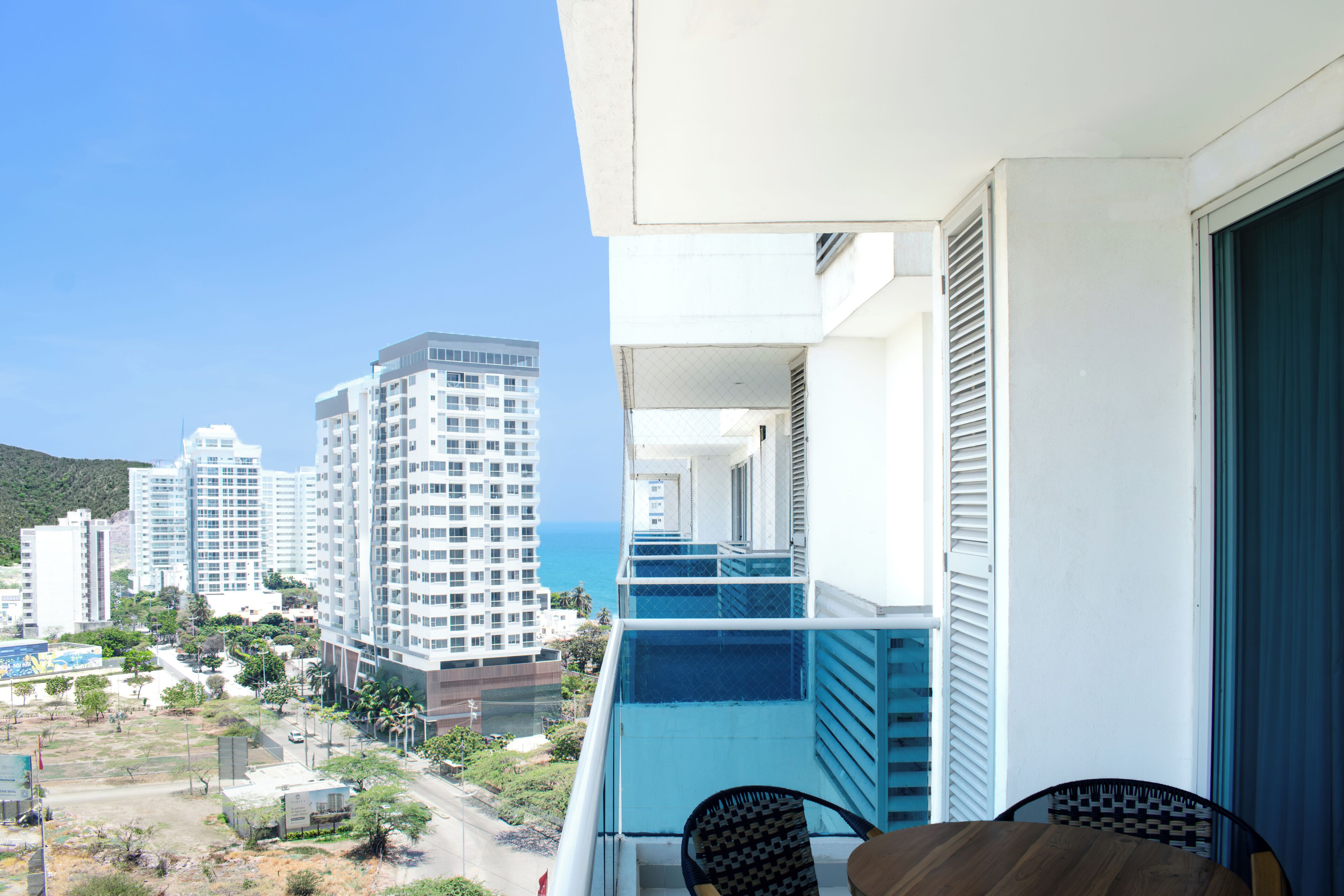 A balcony with a view of a coastal cityscape, including high-rise buildings and a clear sky.