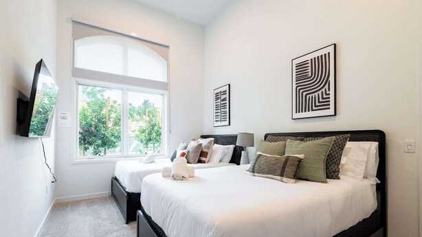 A modern bedroom with two beds, a large window, and artwork on the walls. - Premium 1B1B Living with Pool, Spa and Smart 4K TVs (Montclair)