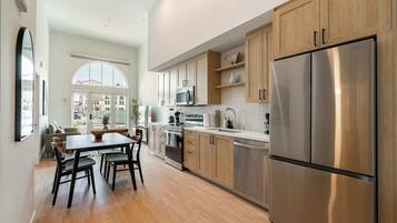 Una cocina moderna con armarios de madera, electrodomésticos de acero inoxidable y una zona de comedor con mesa y sillas.