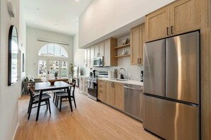 Una cocina moderna con armarios de madera, electrodomésticos de acero inoxidable y una zona de comedor con mesa y sillas.