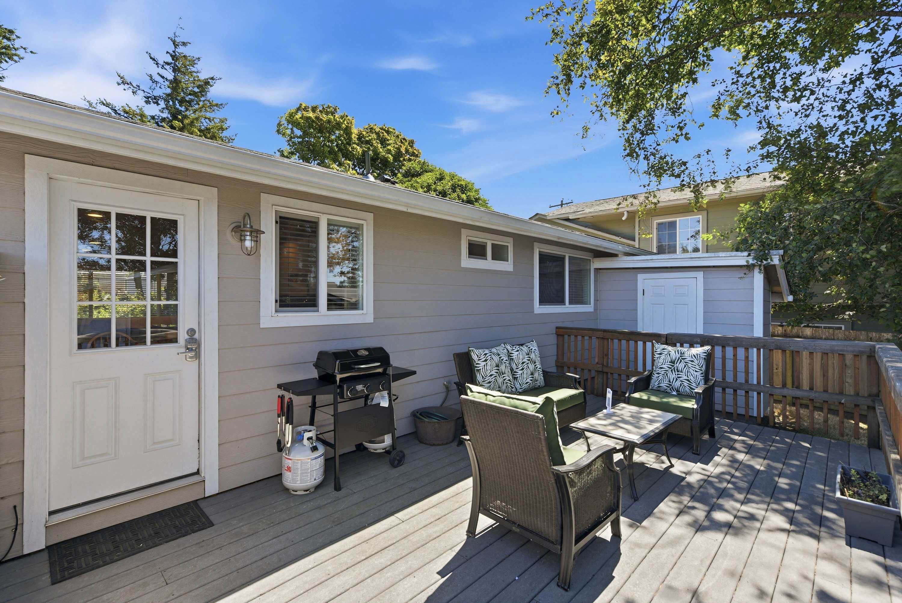 A covered patio with a grill, outdoor furniture, and a door leading to the house.