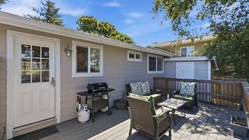 A covered patio with a grill, outdoor furniture, and a door leading to the house.