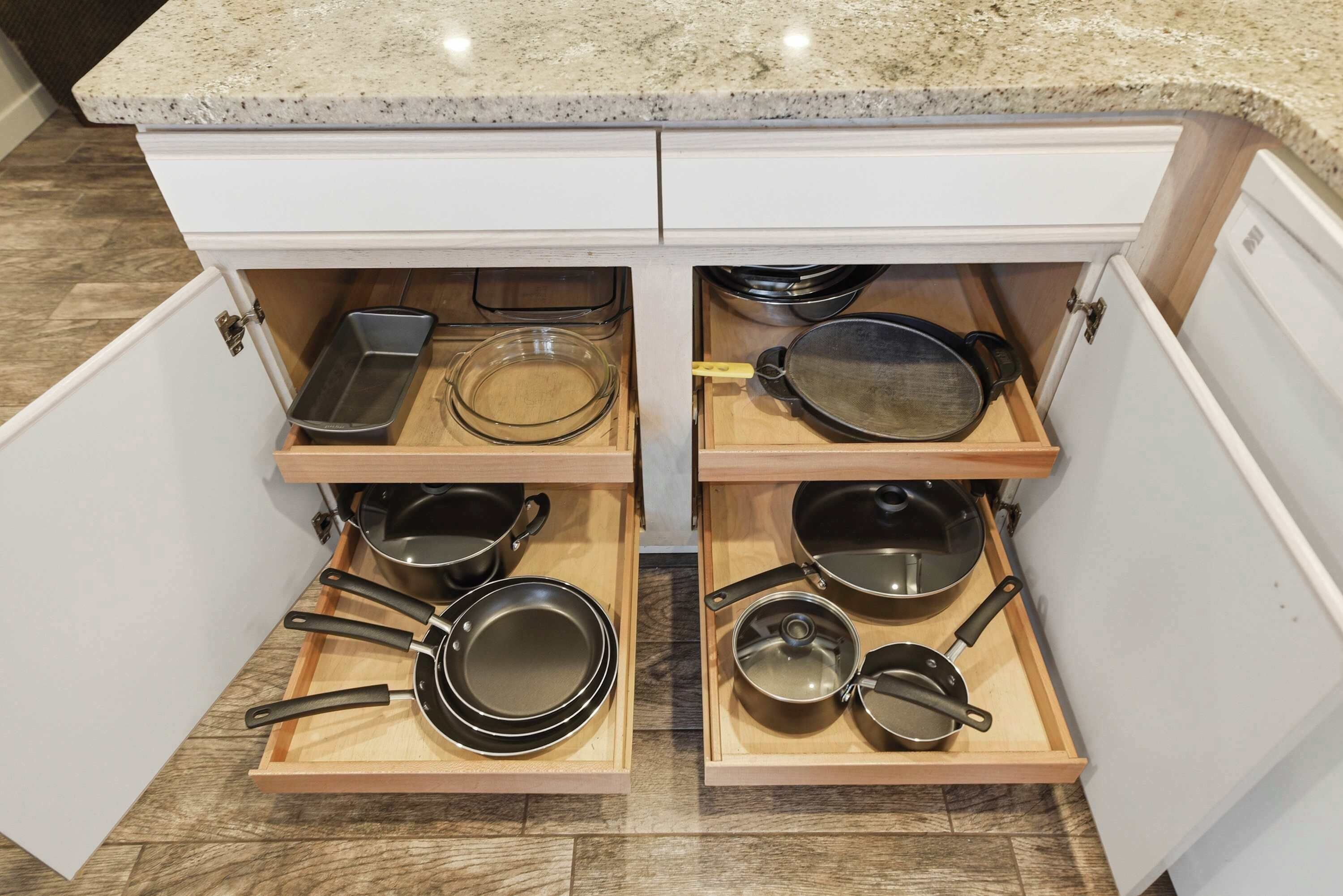 A kitchen with a granite countertop and a built-in drawer unit with multiple compartments for cookware.