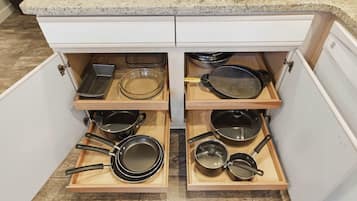 A kitchen with a granite countertop and a built-in drawer unit with multiple compartments for cookware.