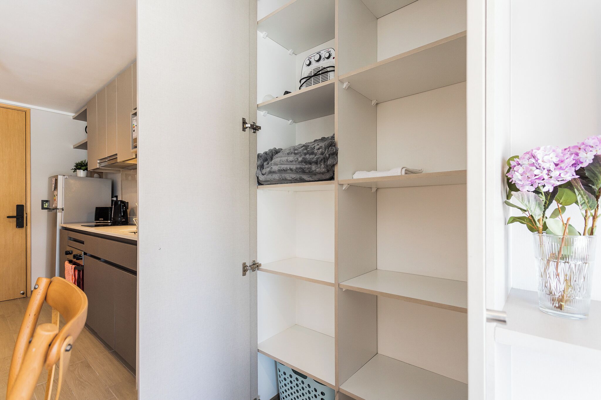 A modern kitchen with a built-in dishwasher, a coffee machine, and a wooden chair.