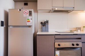 A kitchen with a built-in refrigerator, a stove, and a microwave. - Chic Modern Studio in Nunoa Vibran (Ñuñoa)