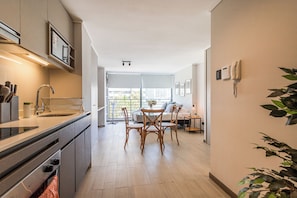 Eine moderne Küche mit Essbereich, einem eingebauten Backofen und einem großen Fenster mit Blick auf die Stadt.