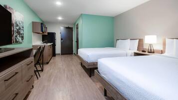 A hotel room with two beds, a desk with a chair, a television, and a door leading to another room.