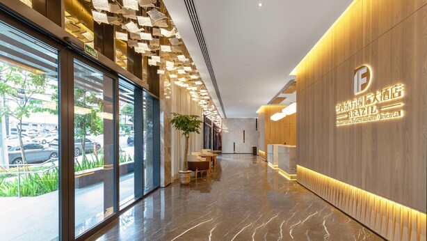 Un moderno vestíbulo de hotel con suelo de mármol, amplias ventanas y una recepción.