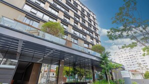Un edificio de varios pisos con una galería techada, vegetación y un letrero de Wyndham Garden.