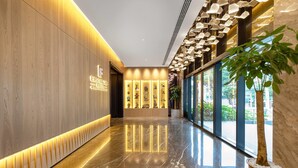 Un corredor moderno de hotel con piso de mármol pulido, paneles de madera y una pared de vidrio con vistas al exterior.