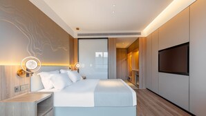 Un dormitorio moderno con una cama grande, mesitas de noche, un televisor y una lámpara fijada a la pared.